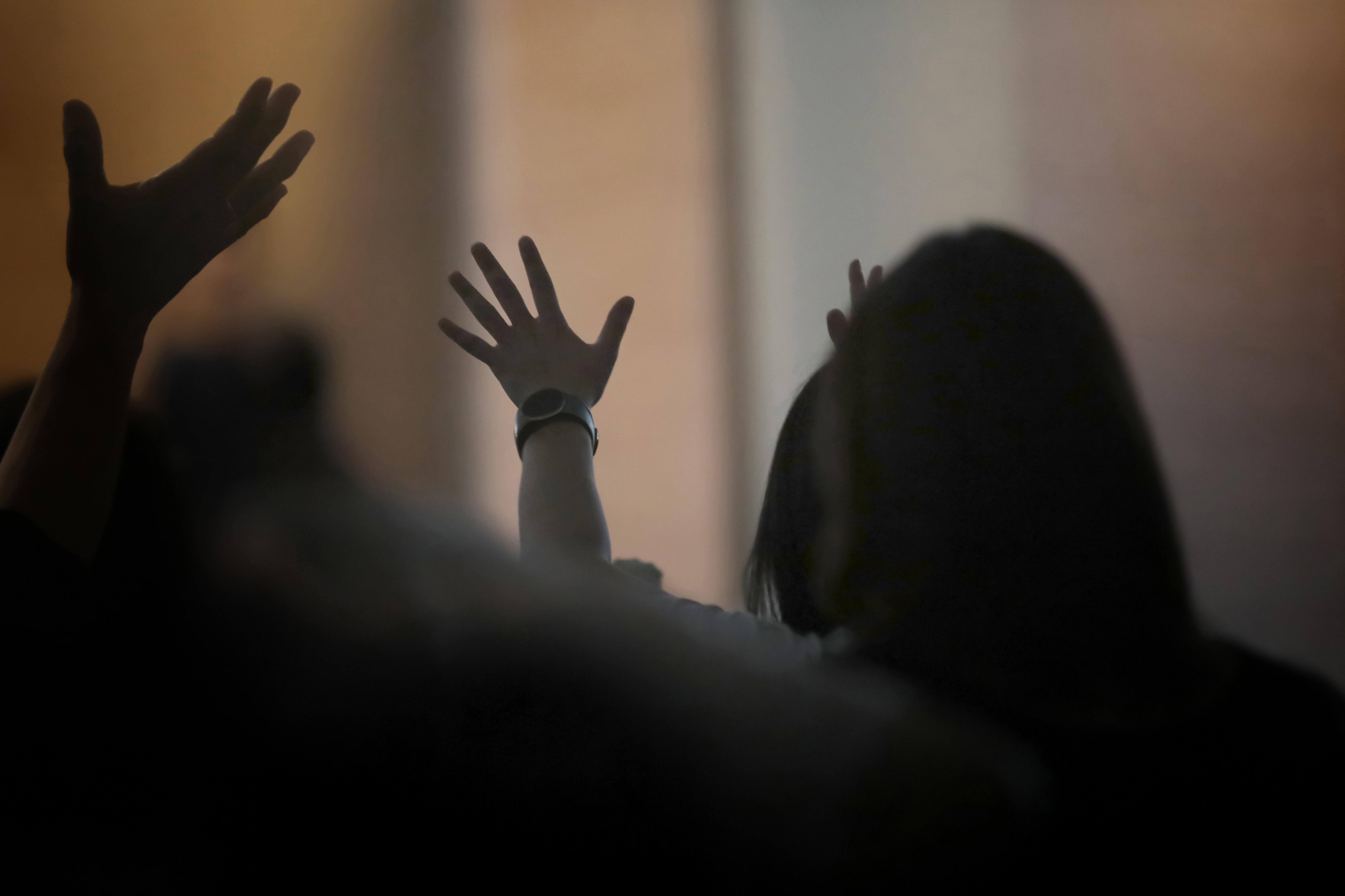 Christians raising their hands to passionately worship, praise, and pray; a Spirit-filled gathering background